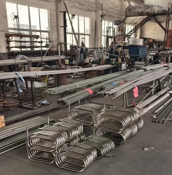Custom-made stainless steel tubing coil in helical form installed inside a heat exchanger system with visible pipe connections